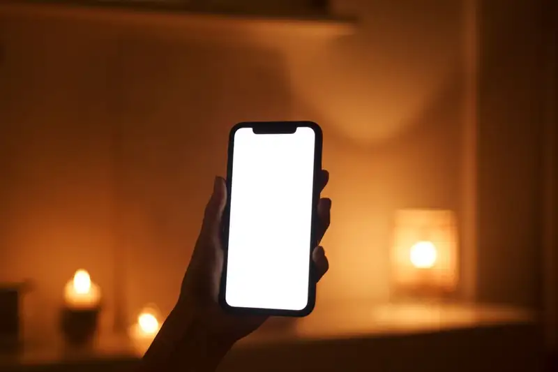 Hand hält ein Smartphone im warm beleuchteten Raum