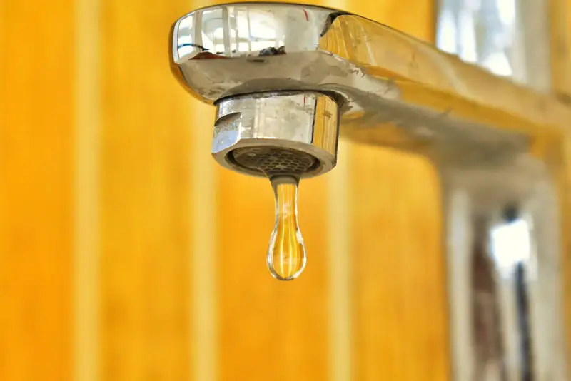 Wassertropfen hängt an einem tropfenden Wasserhahn
